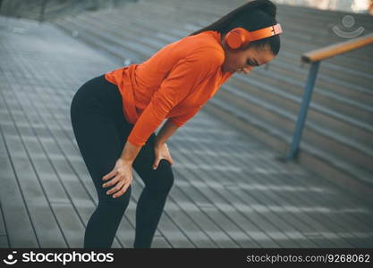 Pretty young woman takes a break after running in urban area