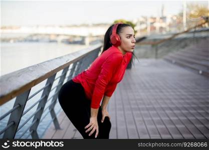 Pretty young woman takes a break after running in urban area