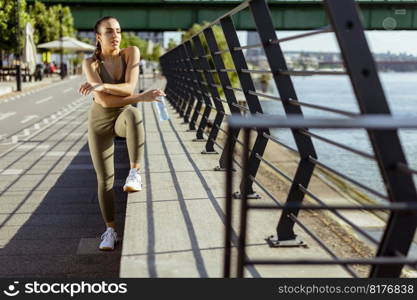 Pretty young woman taking a break during exercise on the river promenade