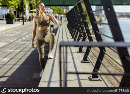 Pretty young woman taking a break during exercise on the river promenade