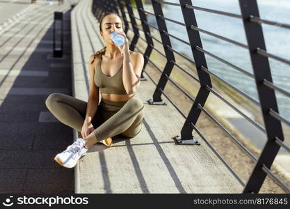 Pretty young woman taking a break during exercise on the river promenade