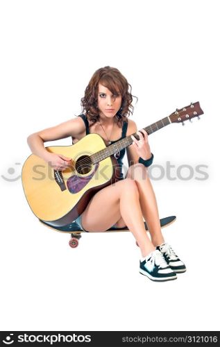 Pretty young woman taking a break from skateboarding playing an acoustic guitar while seated gracefully on the board.