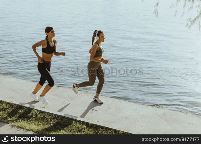 Pretty young woman taking running exercise by the river promenade