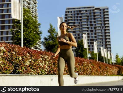 Pretty young woman taking running exercise by the river promenade