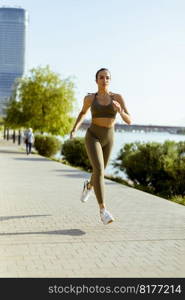 Pretty young woman taking running exercise by the river promenade