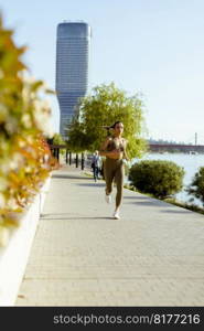 Pretty young woman taking running exercise by the river promenade