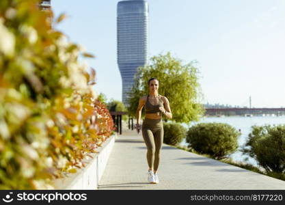 Pretty young woman taking running exercise by the river promenade