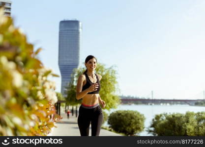 Pretty young woman taking running exercise by the river promenade