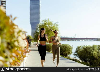 Pretty young woman taking running exercise by the river promenade