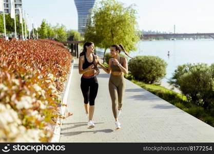 Pretty young woman taking running exercise by the river promenade