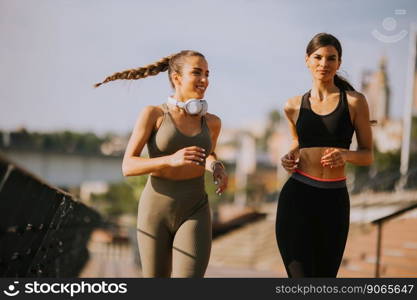 Pretty young woman taking running exercise by the river promenade