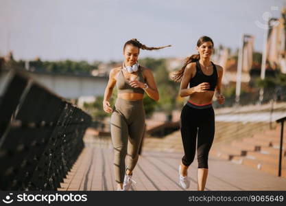 Pretty young woman taking running exercise by the river promenade