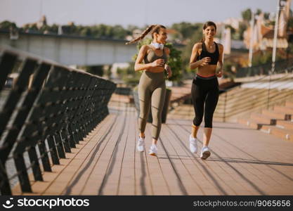 Pretty young woman taking running exercise by the river promenade