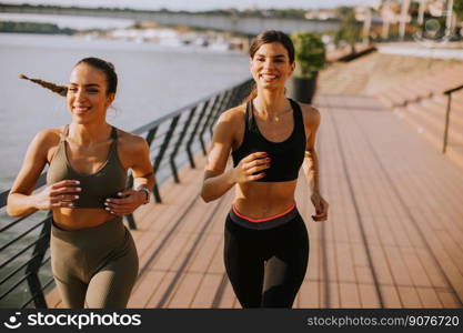 Pretty young woman taking running exercise by the river promenade