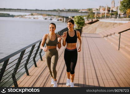 Pretty young woman taking running exercise by the river promenade