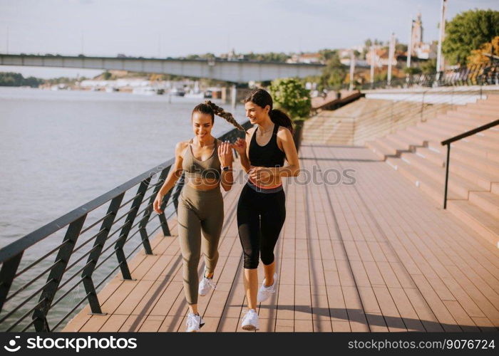 Pretty young woman taking running exercise by the river promenade