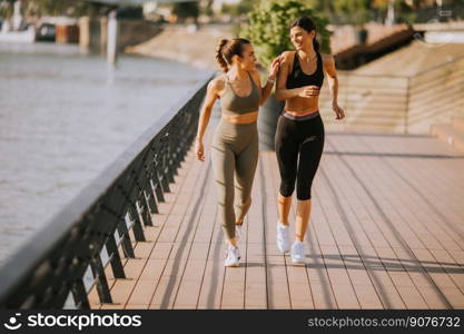 Pretty young woman taking running exercise by the river promenade