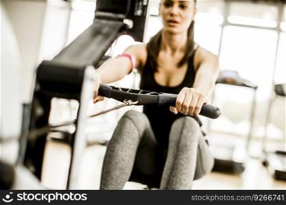 Pretty young woman training on rowing machine in the gym