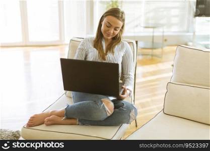 Pretty young woman using a laptop while relaxing on the couch in the room