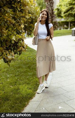 Pretty young woman using a mobile phone while walking on the street