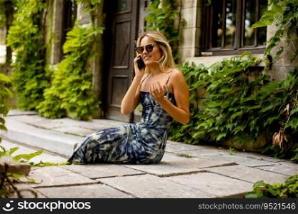 Pretty young woman using mobile phone by old house with ivy