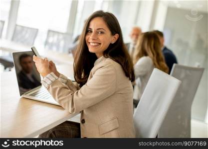 Pretty young woman using mobile phone in the office