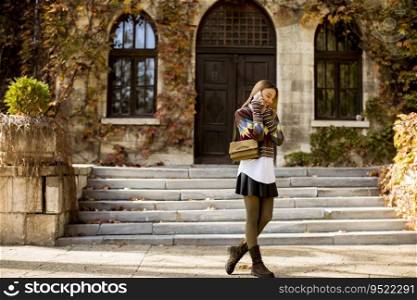 Pretty young woman walking in the autumn park on a sunny day