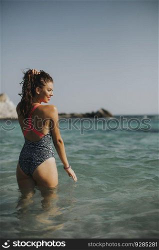 Pretty young woman walking in the warm sea water at summer