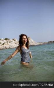 Pretty young woman walking in the warm sea water at summer