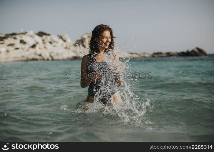 Pretty young woman walking in the warm sea water at summer