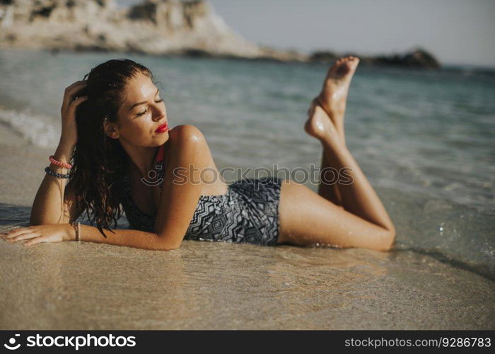 Pretty young woman wearing bikini relaxing on the seashore at summer holiday