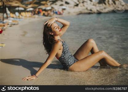 Pretty young woman wearing bikini relaxing on the seashore at summer holiday