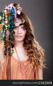Pretty young woman wearing bracelets holding many plentiful of precious jewelry necklaces beads. Portrait of gorgeous fashion girl in studio on gray.. Pretty woman with jewelry necklaces ring bracelets