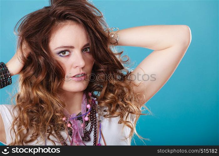 Pretty young woman wearing many plenty of jewelry necklaces beads, rings and bracelets. Portrait of gorgeous fashion girl in studio on blue.. Pretty woman with jewelry necklaces ring bracelets