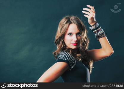 Pretty young woman wearing multiple bracelets jewellery necklace in black elegant evening dress on dark