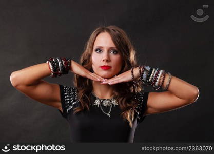 Pretty young woman wearing multiple bracelets jewellery necklace in black elegant evening dress on dark