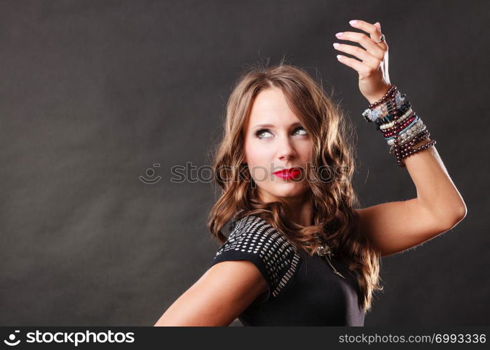 Pretty young woman wearing multiple bracelets jewellery necklace in black elegant evening dress on dark