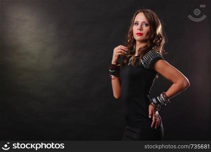 Pretty young woman wearing multiple bracelets jewellery necklace in black elegant evening dress on dark