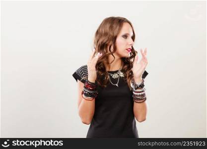 Pretty young woman wearing multiple bracelets jewellery necklace in black elegant evening dress on gray