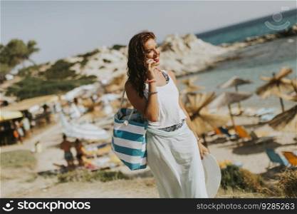 Pretty young woman with a bag on the beach at sunny summer day