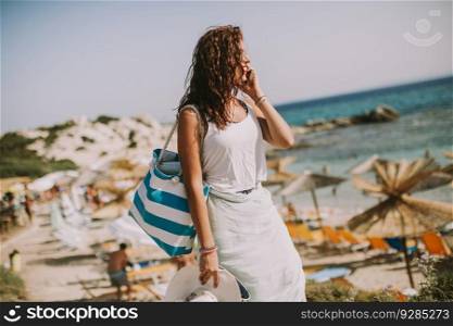 Pretty young woman with a bag on the beach at sunny summer day