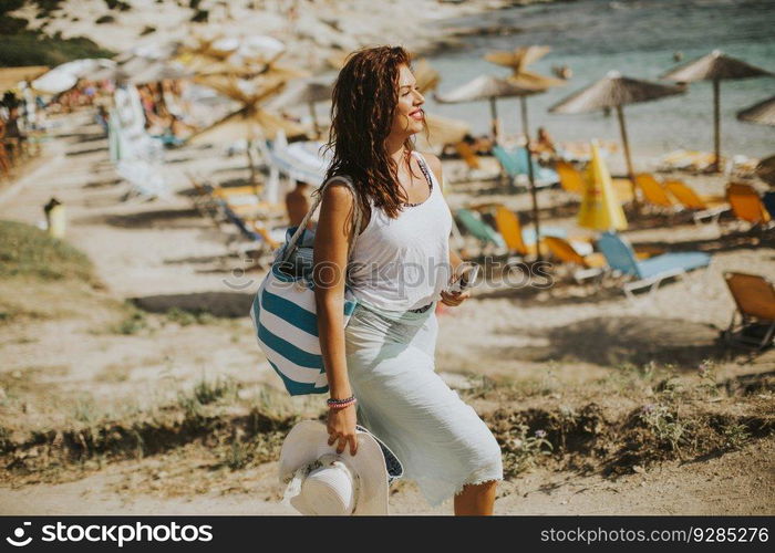 Pretty young woman with a bag on the beach at sunny summer day