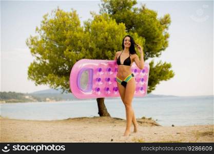 Pretty young woman with a mattress on the beach