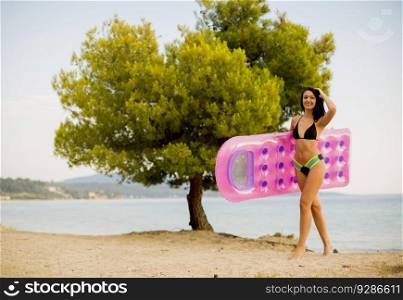 Pretty young woman with a mattress on the beach