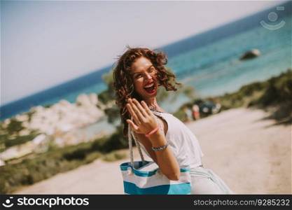 Pretty young woman with bag on the beach on a hot summer day