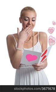 pretty young woman with blonde hair and white dress reading valentine postcard with surprised expression