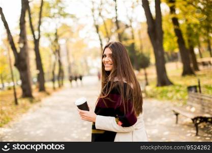 Pretty young woman with coffee cup in the autumn park