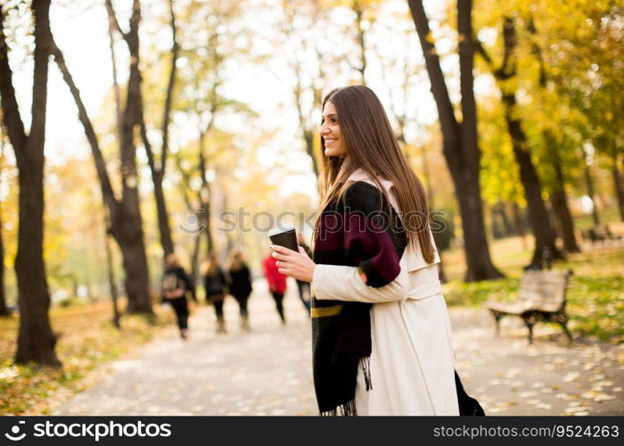 Pretty young woman with coffee cup in the autumn park