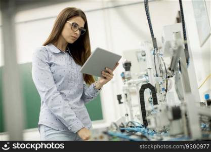Pretty young woman with digital tablet in the electronics workshop