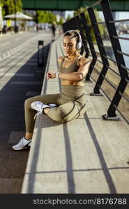 Pretty young woman with earphones takes a break after running in the urban area